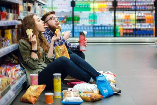 Pärchen futtert ungesunde Snacks im Supermarkt