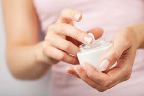 Eine Frau tupft ihren Finger in eine Creme.