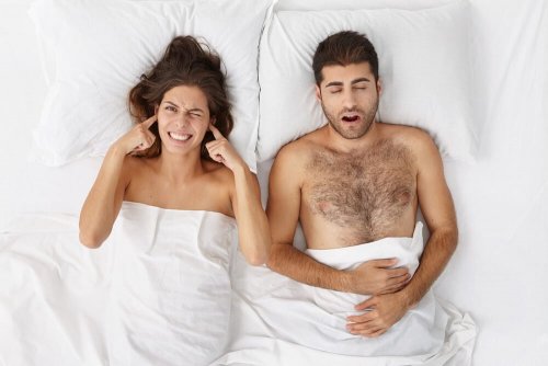 Frau liegt mit schnarchendem Mann im Bett