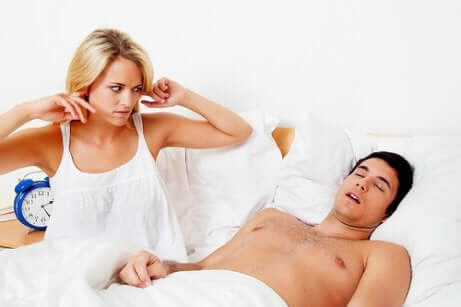 Schlafapnoe-Syndrom (SAS): Frau hält sich die Ohren wegen scharchendem Mann zu