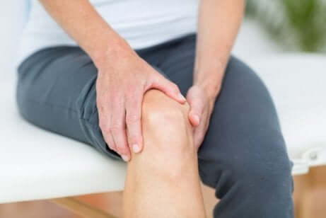 Zwei Hände halten ein schmerzendes Knie