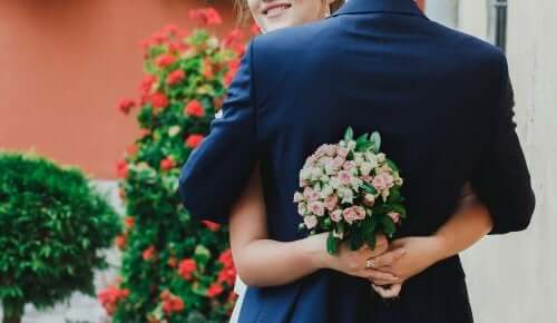 Brautpaar-umarmt-mit-Blumenstrauß