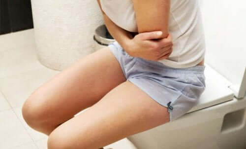 Darmträgheit: Frau sitzt auf Toilette und hat Schmerzen