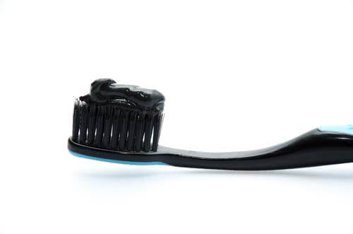 Schwarze Zahnbürste mit schwarzer Zahnpasta