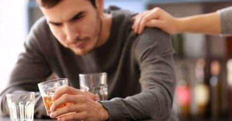 Alkoholiker trinkt mit der Hand einer Person auf seiner Schulter
