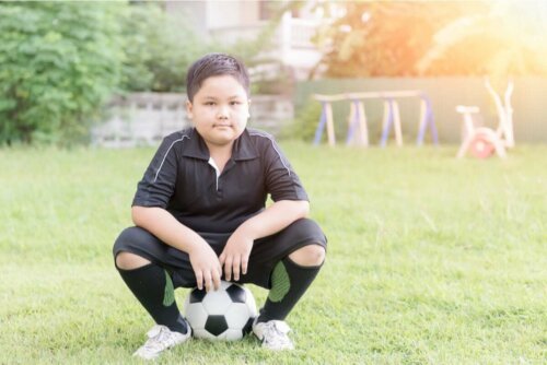 Kindern beibringen - Junge sitzt auf einem Fußball