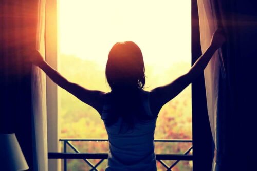 Eine Frau, die an einem sonnigen Tag die Vorhänge öffnet