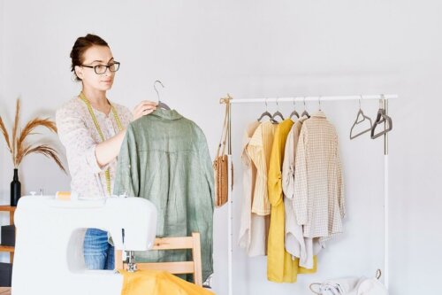 Eine Frau, die Kleidung auf ein Gestell hängt, mit einer Nähmaschine im Vordergrund