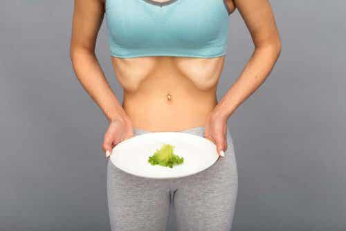 Diabulimie-extrem dünne Frau hält Teller mit einem Stück Salat.