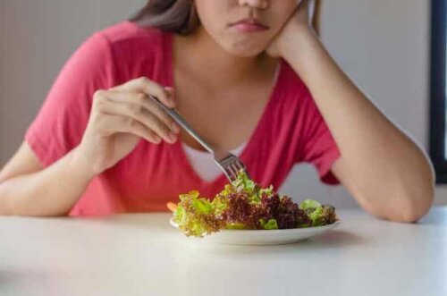 Abnehmen, ohne zu hungern - Frau isst lustlos einen Salat