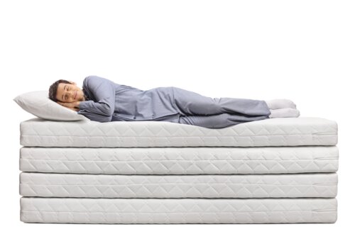 Welche Matratzenhöhe bei Rückenschmerzen? Frau schläft auf mehreren Matratzen.